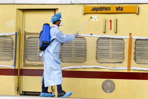 दिल्ली के शकूरबस्ती में कोविड-19 मरीजों की देखभाल के लिए रेलवे कोच में बनाए गए आइसोलेशन वॉर्ड में कीटाणुनाशक का छिड़काव करता कर्मचारी