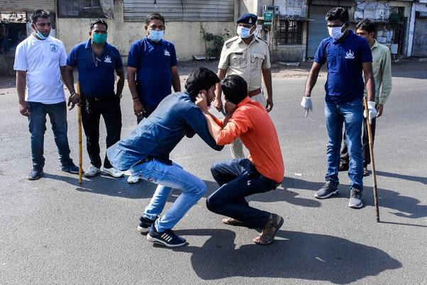 सूरत में लॉकडाउन के दिशानिर्देशों का उल्लंघन करने वालों को दंडित करते पुलिस कर्मी