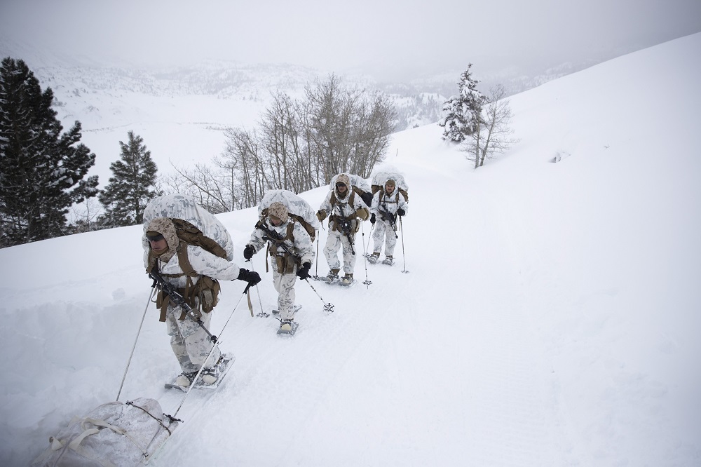 अमेरिकी मरीन का एक समूह मरीन कॉर्प्स माउंटेन वारफेयर ट्रेनिंग सेंटर में प्रशिक्षण के दौरान बर्फ पर चलता हुआ