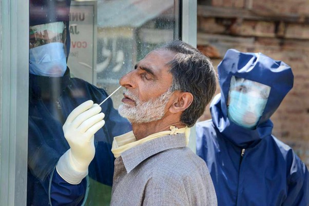 कोरोना वायरस के प्रसार पर अंकुश लगाने के लिए लगाए गए लॉकडाउन के बीच श्रीनगर में कोविड-19 टेस्ट के लिए नमूने लेते स्वास्थ्यकर्मी