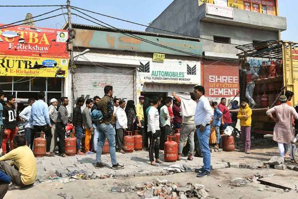 उत्तर-पूर्वी दिल्ली के दंगा प्रभावित क्षेत्र में कमी के बाद एलपीजी सिलेंडर लेने के लिए कतार में खड़े स्थानीय लोग