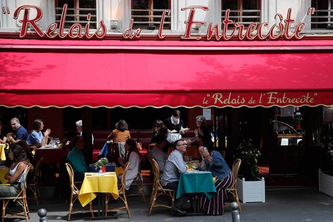 पेरिस में रेस्टोरेंट में लंच के दौरान सेल्फी लेते ग्राहक। कोविड-19 के चलते 14 मार्च को बंद होने के बाद अब खुले पेरिस के रेस्टोरेंटों में सब कुछ बदला हुआ है। उन्हें ग्राहकों को बाहर भोजन परोसने की तो अनुमति है लेकिन वे अंदर नहीं बिठा सकते हैं।