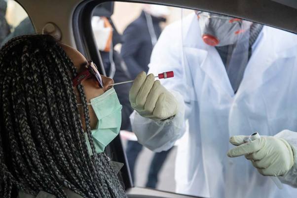 पेरिस के कोरोना वायरस के एक जांच केंद्र में बायोलॉजिस्ट क्रिस्टोफर डिलॉने एक चालक को नाक की दवा देते हुए