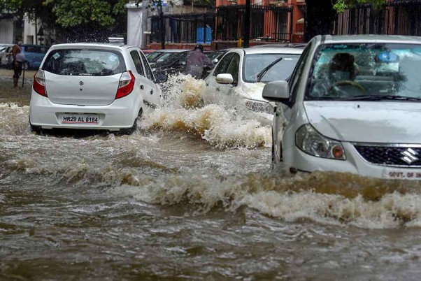 राजधानी दिल्ली में मानसून की बौछार के बाद भारी जलभराव वाले महादेव रोड पर चलती गाड़ियां