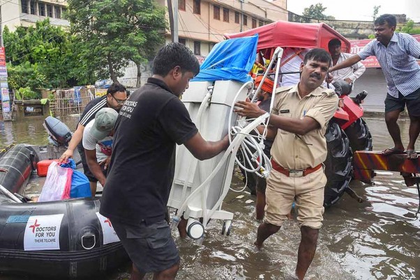 पटना के वैशाली में बाढ़ से प्रभावित अस्पताल से मेडिकल वेंटिलेटर मशीन ले जाता पुलिसकर्मी