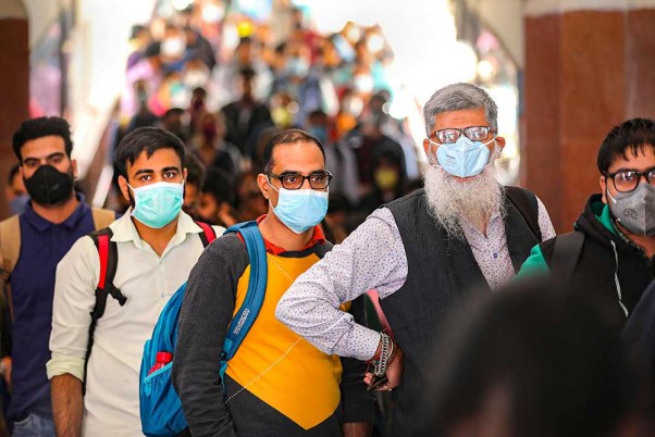 कोरोनावायरस के खिलाफ एहतियात के तौर पर जम्मू में एक रेलवे स्टेशन पर मास्क पहने यात्री