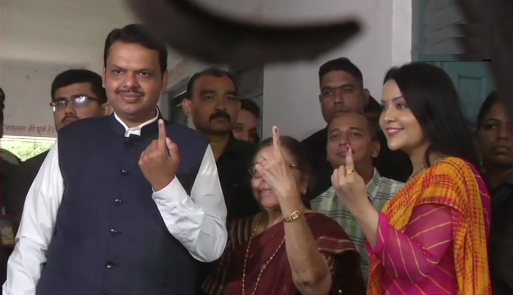 नागपुर के एक मतदान केंद्र पर वोट डालने के बाद मुख्यमंत्री देवेंद्र फडनवीस, पत्नी अमृता और मां सरिता के साथ