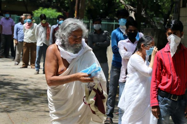 कोरोना वायरस के प्रसार को रोकने के लिए लॉकडाउन के बीच राजधानी दिल्ली के शाहपुरजट क्षेत्र में लोगों को फेस मास्क वितरित करते स्वयंसेवक