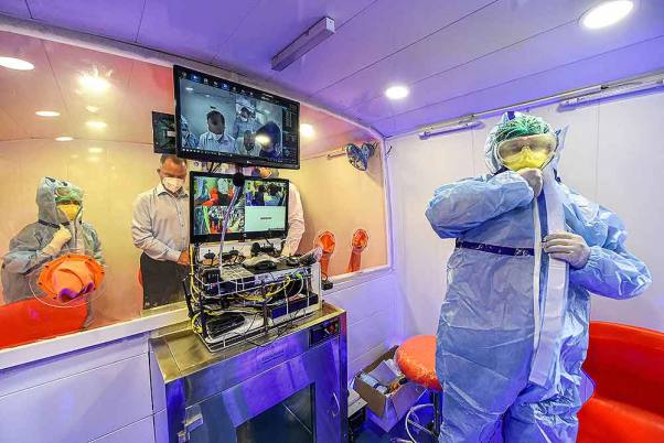 राजधानी दिल्ली में मोबाइल कोरोना वायरस टेस्ट सुविधा बस के अंदर सुरक्षात्मक सूट पहने स्वास्थ्यकर्मी