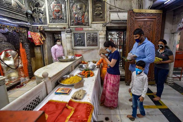 लॉकडाउन के बीच अधिकारियों द्वारा कुछ प्रतिबंधों के साथ सभी धार्मिक स्थानों को खोलने की अनुमति देने के बाद दिल्ली के हनुमान मंदिर में प्रार्थना करते श्रद्धालु