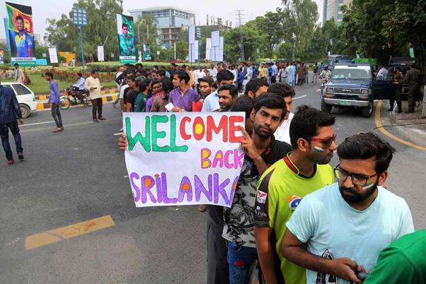 पाकिस्तान के लाहौर में श्रीलंका और पाकिस्तान के बीच पहला टी-20 मैच से पहले गद्दाफी स्टेडियम में सुरक्षा जांच के लिए कतार में क्रिकेट प्रशंसक