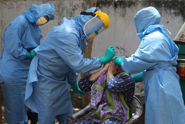 कोरोना वायरस के प्रसार को नियंत्रित करने के लिए अहमदाबाद के एक स्वास्थ्य केंद्र में महिला की जांच करती मेडिकल टीम