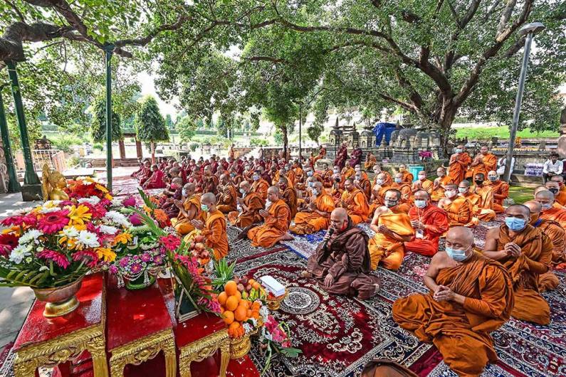 बोधगया में पवित्र बोधि वृक्ष के नीचे प्रार्थना करते बौद्ध भिक्षु