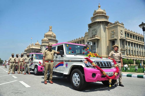 बेंगलूरु में विधाना सौध में बैंगलोर मेट्रोपॉलिटन ट्रांसपोर्ट कॉरपोरेशन द्वारा महिला सुरक्षा के लिए लॉन्च की गई गुलाबी सारथी वाहनों के आगे खड़े पुलिसकर्मी