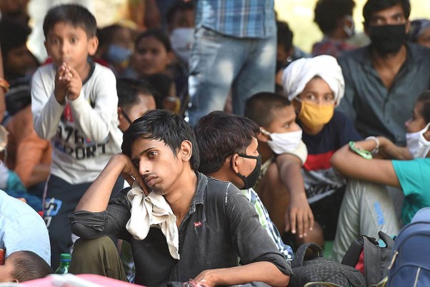यूपी में अपने मूल स्थानों पर जाने के लिए राजधानी दिल्ली के अराम बाग इलाके में एक स्कूल के अंदर बैठकर बसों का इंतजार करते प्रवासी श्रमिक