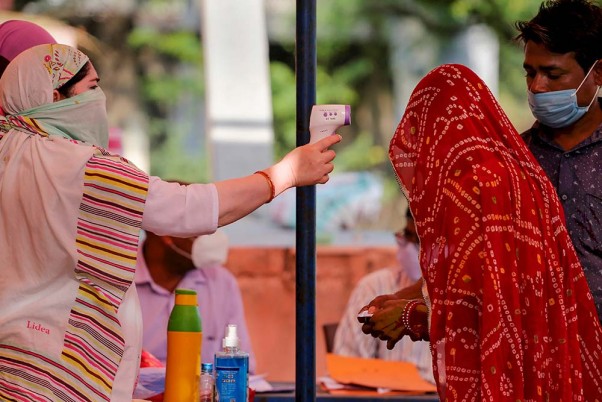 अजमेर में पंचायत चुनाव के दौरान एक मतदान केंद्र के बाहर थर्मल स्कैनिंग करवाते मतदाता