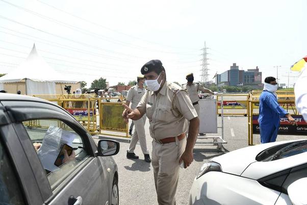 लॉकडाउन के बीच हरियाणा सरकार द्वारा दिल्ली-गुरुग्राम सीमा को सील किए जाने के बाद बॉर्डर पर यात्रियों को रोकते पुलिसकर्मी