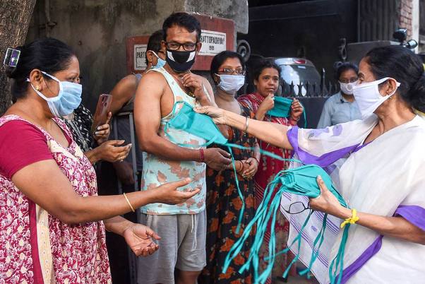 कोरोना वायरस के मद्देनजर कोलकाता में एक राशन की दुकान के पास खड़े लोगों के बीच मास्क वितरित करती पश्चिम बंगाल की मुख्यमंत्री ममता बनर्जी