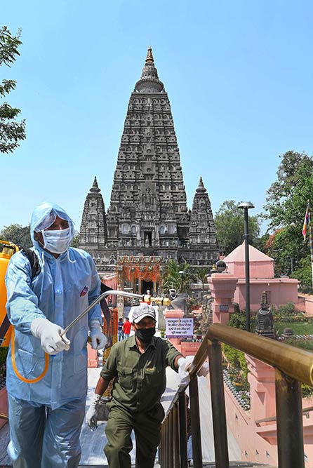 महाबोधि मंदिर के परिसर में कोरोनावायरस के खिलाफ एहतियात के तौर पर बोधगया में कीटाणुनाशक का छिड़काव करता एक कार्यकर्ता