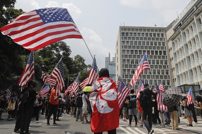 हांगकांग में एक विरोध प्रदर्शन के दौरान संयुक्त राज्य अमेरिका के झंडे के साथ प्रदर्शनकारी