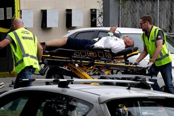 न्यूजीलैंड के क्राइस्टचर्च शहर के मस्जिद में फायरिंग बाद एम्बुलेंस कर्मचारी एक घायल व्यक्ति को ले जाते हुए