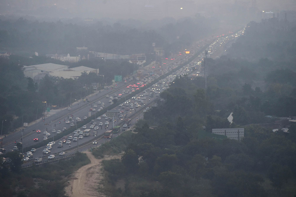 नई दिल्ली में घनी धुंध की चादर के बीच सड़कों पर दौड़ती गाड़ियां