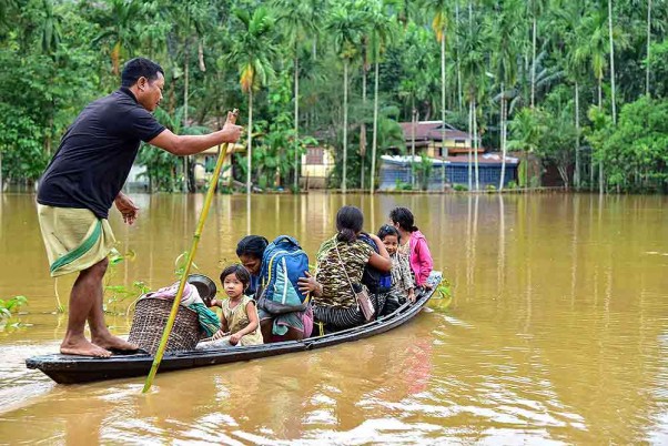 असम के गोआलपाड़ा जिले के बोलबोला में भारी वर्षा के बाद बाढ़ वाले इलाके से नाव के जरिये दूसरे इलाके में परिवार को लेकर जाता ग्रामीण