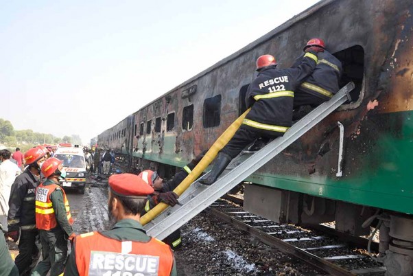 पाकिस्तान के लियाकतपुर में आग लगने से क्षतिग्रस्त हुई ट्रेन में बचे लोगों की तलाश करते बचावकर्मी