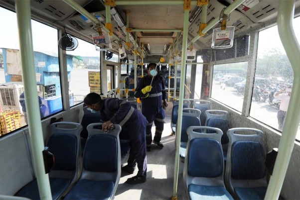 कोरोनो वायरस के खिलाफ एहतियात के तौर पर यात्री बस को साफ करता दिल्ली परिवहन निगम का एक कर्मी