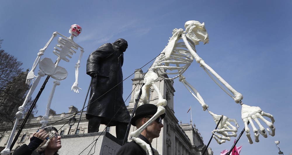 लंदन में विंस्टन चर्चिल की प्रतिमा के पास कंकाल लेकर जलवायु संरक्षण के लिए प्रदर्शन करते लोग