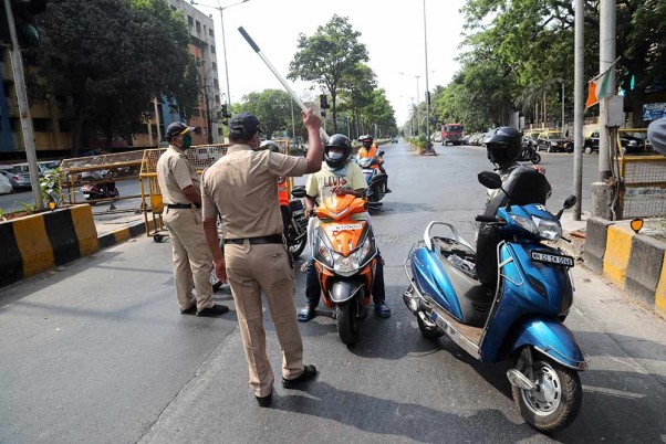 देशभर में लॉकडाउन के दौरान मुंबई में सड़कों पर जाने वाले वाहनों को रोकते पुलिस अधिकारी