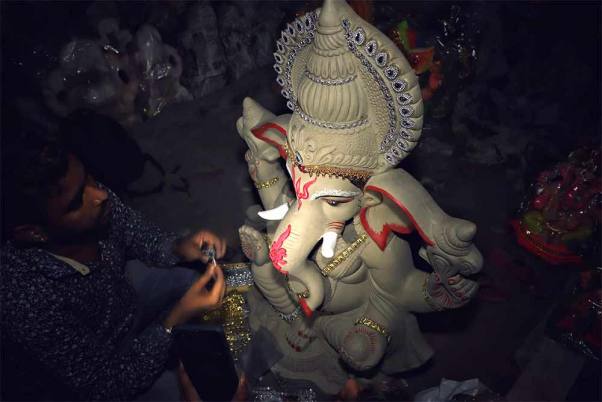 नई दिल्ली में गणेश चतुर्थी उत्सव से पहले अपनी कार्यशाला में भगवान गणेश की मूर्तियों को फिनिशिंग टच देते कलाकार