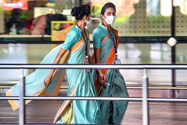 मुंबई के अंतरराष्ट्रीय हवाई अड्डे पर कोरोना वायरस से बचाव के लिए मास्क पहनीं कर्मचारी
