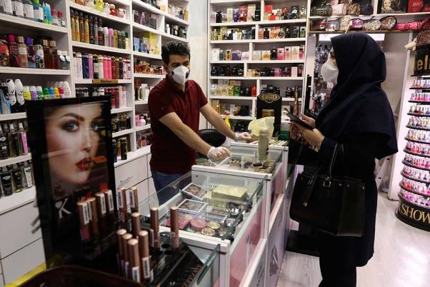 कोरोना वायरस के मद्देनजर तेहरान के कोरोश शॉपिंग सेंटर में कॉस्मेटिक की दुकान में सुरक्षात्मक फेस मास्क पहने हुए दुकानदार और ग्राहक