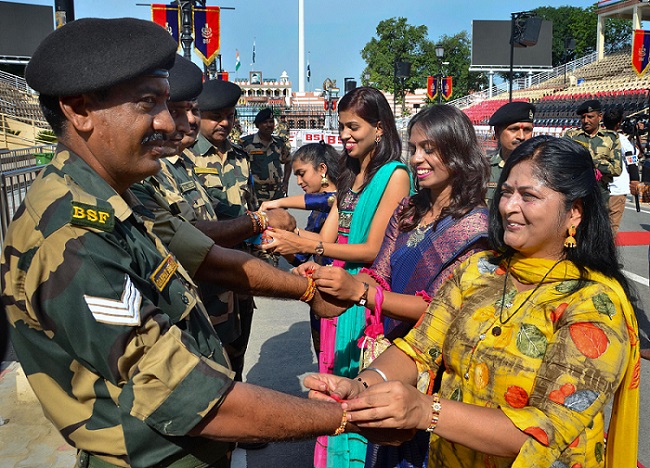 अटारी-वाघा सीमा पर रक्षा बंधन त्योहार के दौरान सीमा सुरक्षा बल (बीएसएफ) के जवानों की कलाई पर राखी बांधती महिलाएं