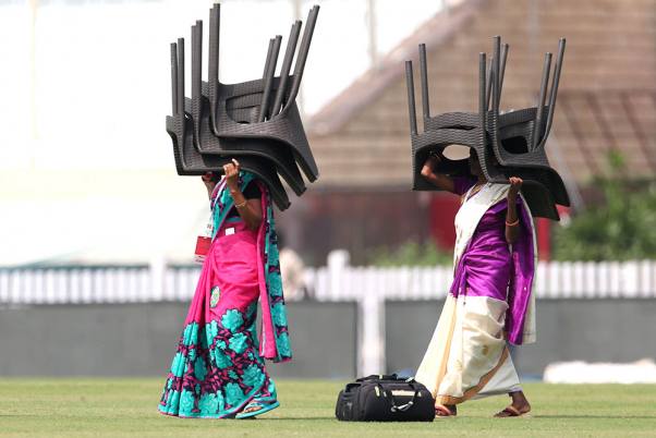 रांची में दक्षिण अफ्रीका के खिलाफ तीसरे और आखिरी क्रिकेट टेस्ट मैच से पहले भारतीय टीम के एक ट्रेनिंग सेशन के दौरान मैदान में कुर्सियां ले जाती महिला कार्यकर्ता
