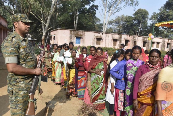 झारखंड में जारी विधानसभा चुनाव के पहले चरण के मतदान के बीच कड़ी सुरक्षा के बीच वोट डालते लोग