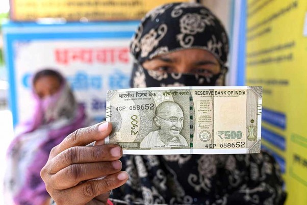 लॉकडाउन के बीच जबलपुर में जनधन अकाउंट से पैसे निकालने के बाद बैंक के बाहर 500 रुपये का नोट दिखाती महिला