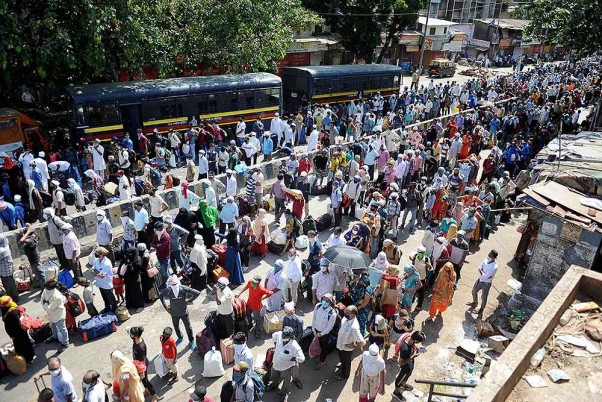 मुंबई में चल रहे लॉकडाउन के दौरान विशेष ट्रेन द्वारा अपने मूल स्थानों तक पहुंचने के लिए रेलवे स्टेशन जाने के लिए धारावी में बसों का इंतजार करते प्रवासी