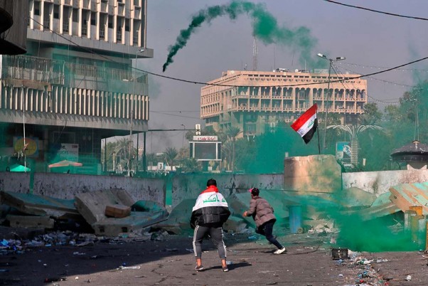 बगदाद में इराकी सुरक्षा बलों और सरकार विरोधी प्रदर्शनकारियों के बीच झड़प के दौरान आंसू गैस और स्मोक बम दागती पुलिस