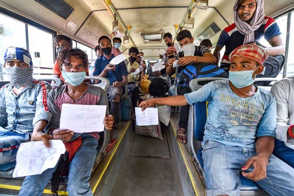 नई दिल्ली में यमुना स्पोर्ट्स कॉम्प्लेक्स में रेलवे स्टेशन जाने वाली बस में बैठने के दौरान अपना मेडिकल सर्टिफिकेट दिखाते पश्चिम बंगाल जाने वाले प्रवासी