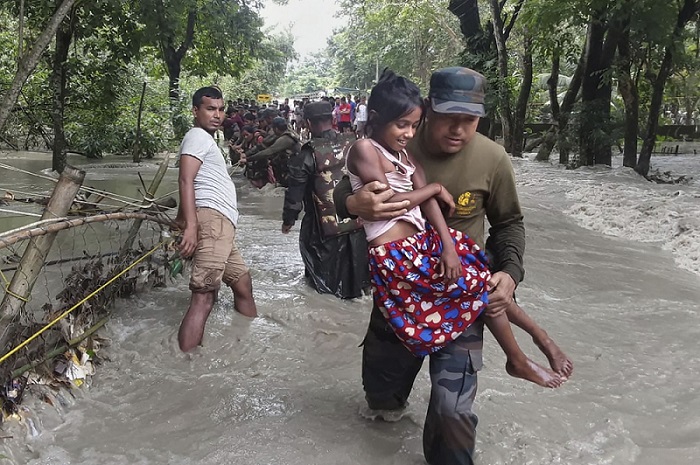 असम के नलबाड़ी में बाढ़ प्रभावित गांव से ग्रामीणों को सुरक्षित स्थानों पर ले जाते भारतीय सेना के जवान