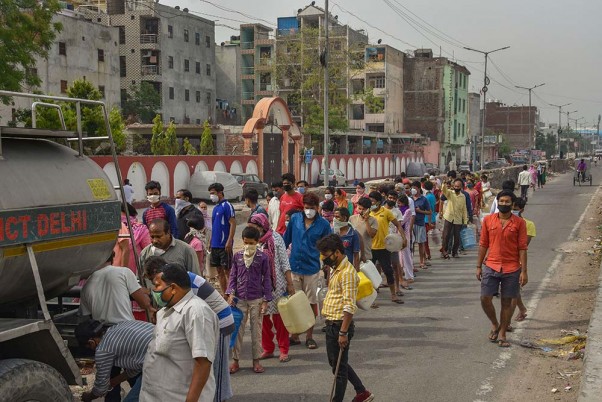 दिल्ली के न्यू अशोक नगर में सोशल डिस्टेंसिंग को नजरअंदाज करते हुए पानी के टैंकर से पानी लेने के लिए खड़े लोग