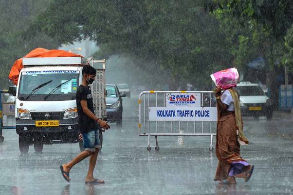 ‘अम्फान’ तूफान के कारण कोलकाता में बदला मौसम, तेज बारिश के बीच सड़कों पर चलते लोग