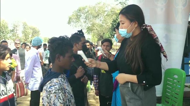 कोरोनोवायरस के प्रसार के खिलाफ भारत-नेपाल सीमावर्ती शहर काकरविट्टा में भारत से आने वाले लोगों की थर्मल स्क्रीनिंग करती महिला