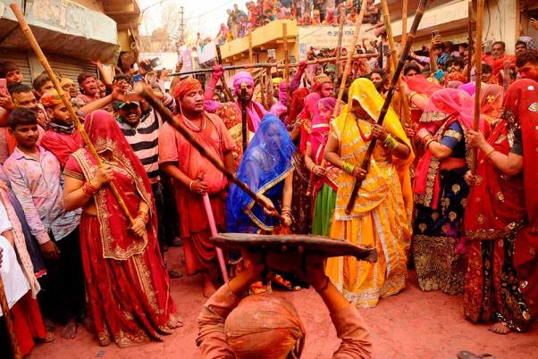 बरसाना में शुरू लठमार होली उत्सव समारोह के दौरान नंदगांव के ग्रामीण को डंडे से पीटती गांव की महिलाएं