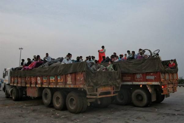 लॉकडाउन के दौरान अपने मूल स्थानों पर जाने के लिए उत्तर प्रदेश के आगरा एक्सप्रेस-वे पर सामान से लदे हुए ट्रक में यात्रा करते प्रवासी मजदूर
