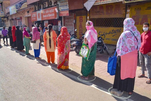 देशव्यापी लॉकडाउन के बीच मथुरा के एक बैंक के बाहर कतार में निश्चित दूरी बनाकर खड़ी महिलाएं