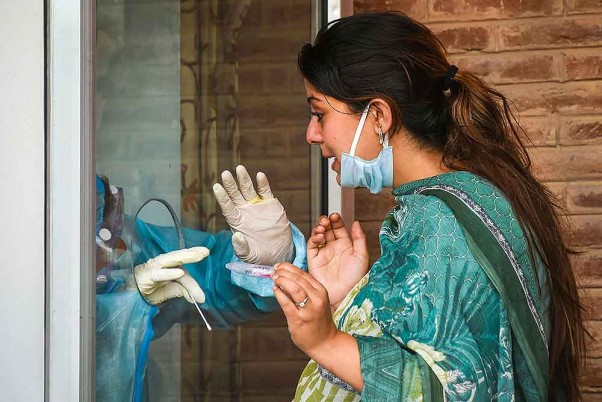 श्रीनगर में अनलॉक 2.0 के दौरान कोविड-19 परीक्षण के लिए एक महिला से नमूने लेता स्वास्थ्य अधिकारी
