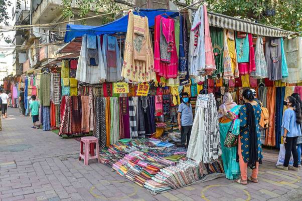 राजधानी दिल्ली में लॉकडाउन के दौरान प्रतिबंधों में ढील दिए जाने के बाद लाजपत नगर सेंट्रल मार्केट में सड़क किनारे लगी दुकानों से कपड़े खरीदते लोग